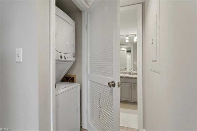 laundry room with stacked washer / dryer and light tile patterned floors