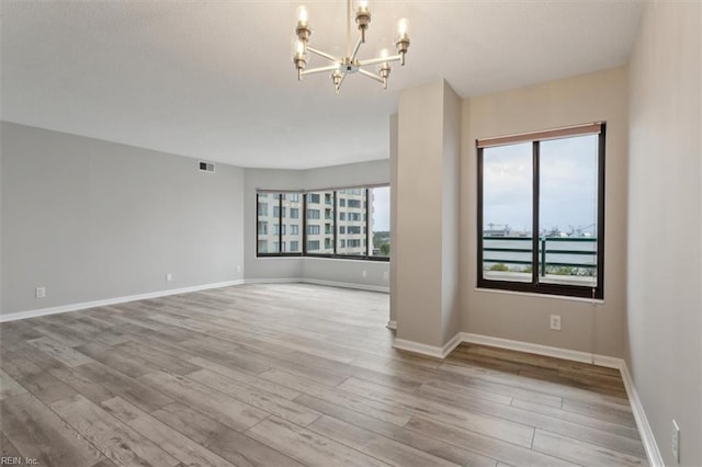 empty room featuring light hardwood / wood-style floors and a chandelier