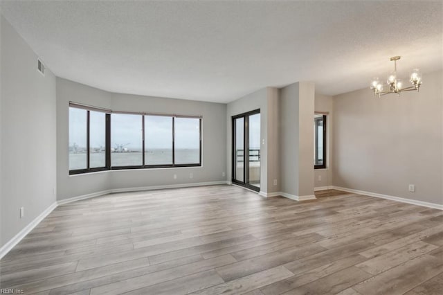 unfurnished room featuring a notable chandelier and light wood-type flooring