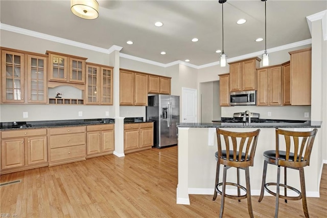 kitchen with pendant lighting, appliances with stainless steel finishes, crown molding, and light hardwood / wood-style flooring