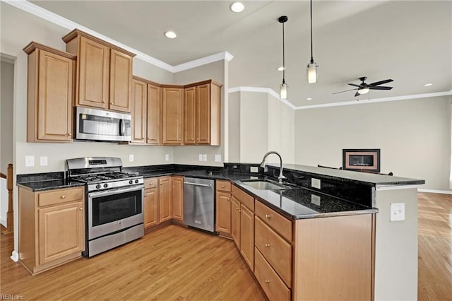 kitchen featuring kitchen peninsula, sink, light wood-type flooring, appliances with stainless steel finishes, and decorative light fixtures