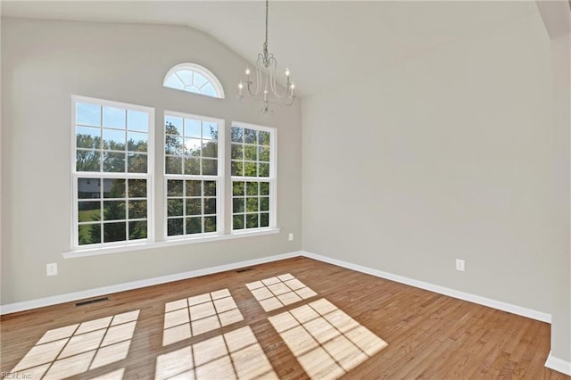 unfurnished dining area with hardwood / wood-style flooring, an inviting chandelier, and lofted ceiling