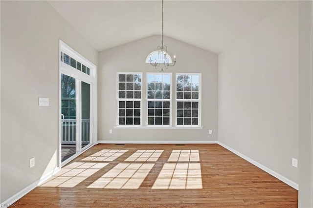 unfurnished dining area featuring wood-type flooring, vaulted ceiling, and a notable chandelier