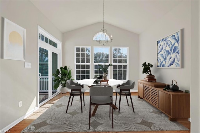 dining space featuring light hardwood / wood-style floors, lofted ceiling, and a chandelier