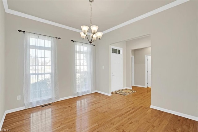 unfurnished room featuring wood-type flooring, an inviting chandelier, and ornamental molding