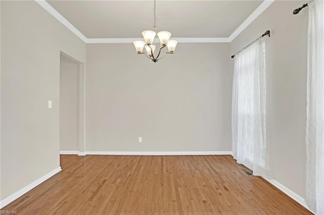 empty room featuring an inviting chandelier, light wood-type flooring, and crown molding