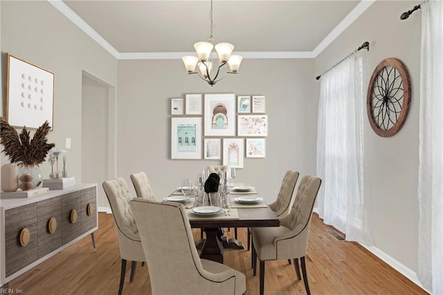 dining room with light wood-type flooring, a chandelier, and crown molding