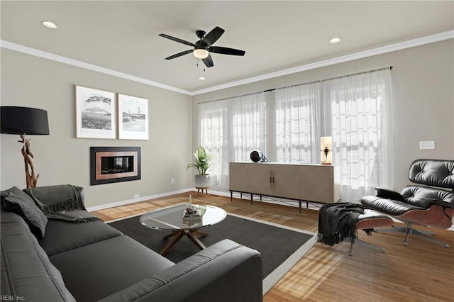 living room featuring wood-type flooring, ceiling fan, and crown molding