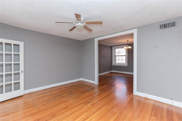 unfurnished room featuring hardwood / wood-style flooring and ceiling fan with notable chandelier