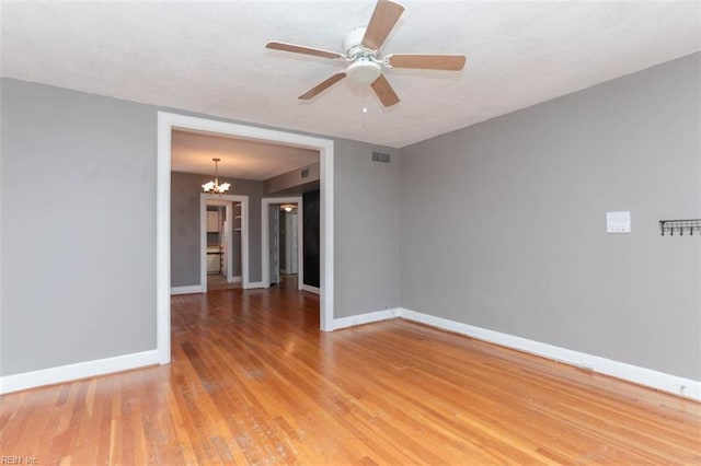 empty room featuring hardwood / wood-style flooring and ceiling fan with notable chandelier