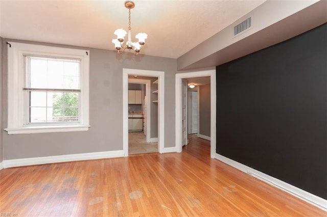 unfurnished room featuring hardwood / wood-style flooring and an inviting chandelier