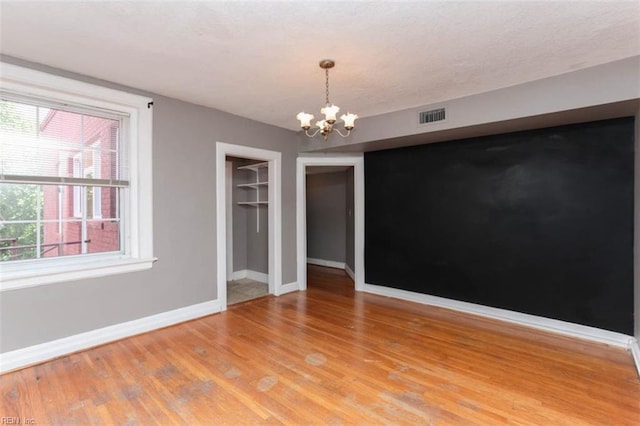 spare room featuring a chandelier and light wood-type flooring