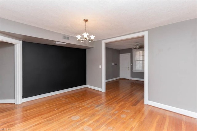 interior space with a textured ceiling, hardwood / wood-style flooring, and ceiling fan with notable chandelier