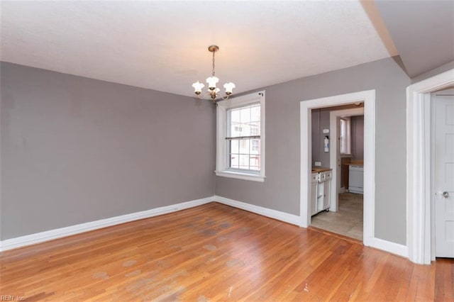 empty room featuring a chandelier and light wood-type flooring