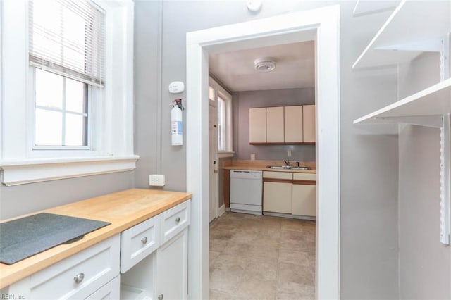 kitchen featuring white cabinetry, dishwasher, wooden counters, and sink