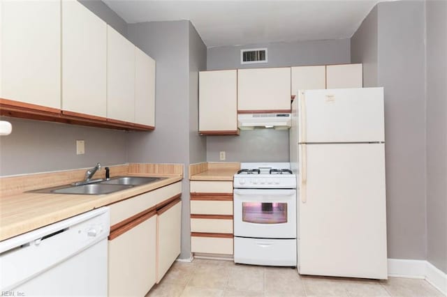 kitchen with white cabinets, sink, light tile patterned floors, and white appliances