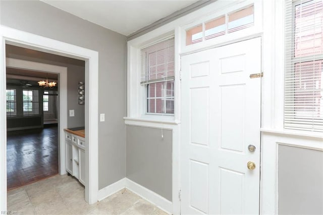 foyer entrance with a wealth of natural light, light hardwood / wood-style flooring, and an inviting chandelier