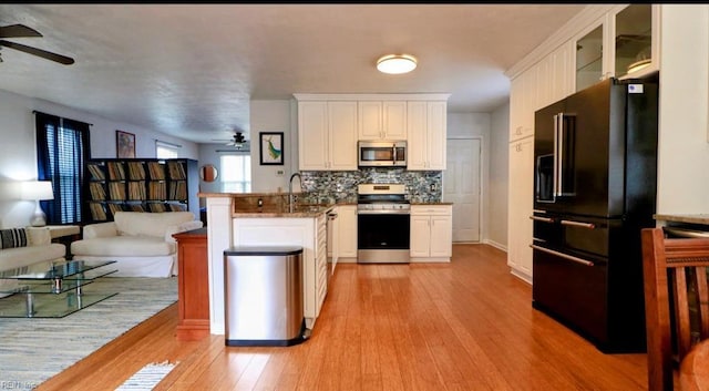 kitchen featuring kitchen peninsula, appliances with stainless steel finishes, backsplash, light hardwood / wood-style flooring, and white cabinets