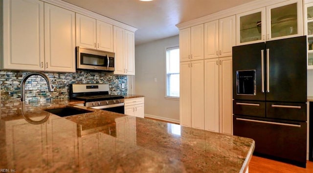 kitchen featuring sink, white cabinetry, stainless steel appliances, and dark stone counters