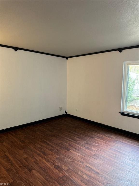 spare room with crown molding, a textured ceiling, and dark hardwood / wood-style flooring