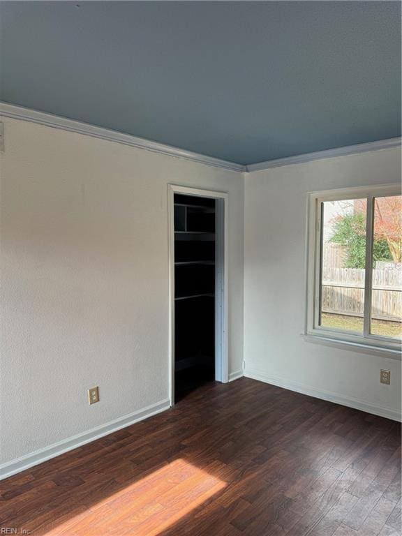 empty room featuring crown molding and dark hardwood / wood-style flooring