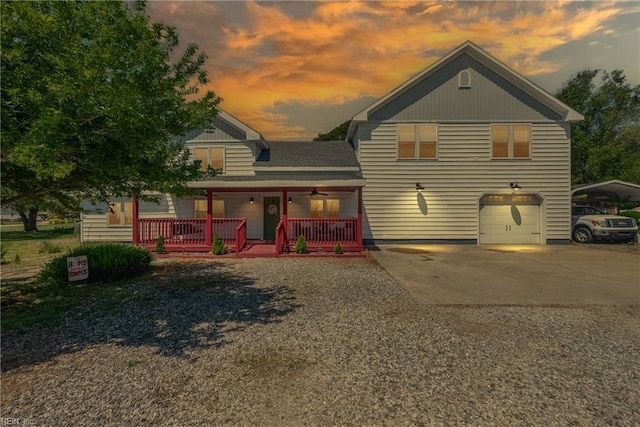 back house at dusk featuring covered porch and a garage