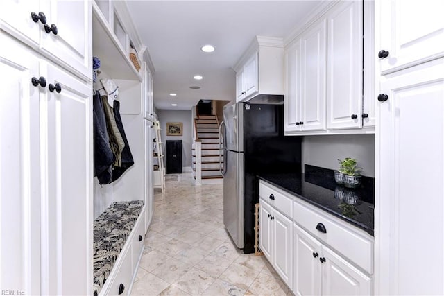 kitchen with dark stone counters, stainless steel refrigerator, and white cabinetry