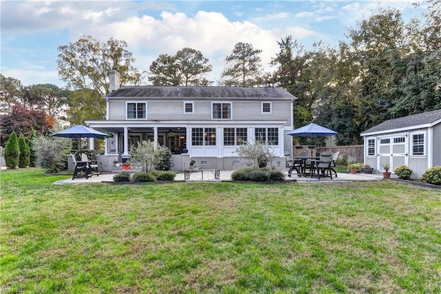 rear view of property with a shed, a yard, and a patio