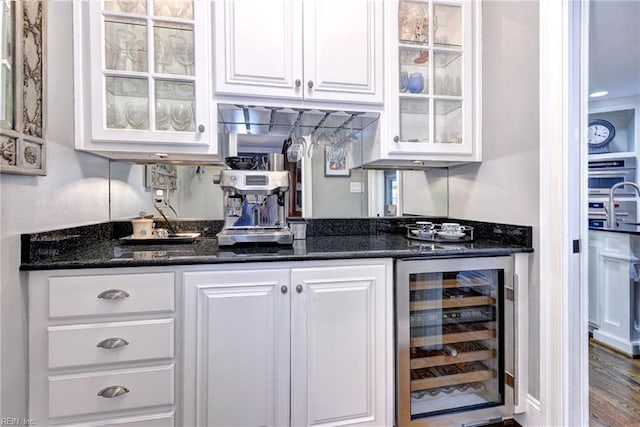 bar featuring wine cooler, sink, dark stone countertops, hardwood / wood-style floors, and white cabinets