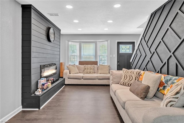 living room with a large fireplace and dark hardwood / wood-style flooring