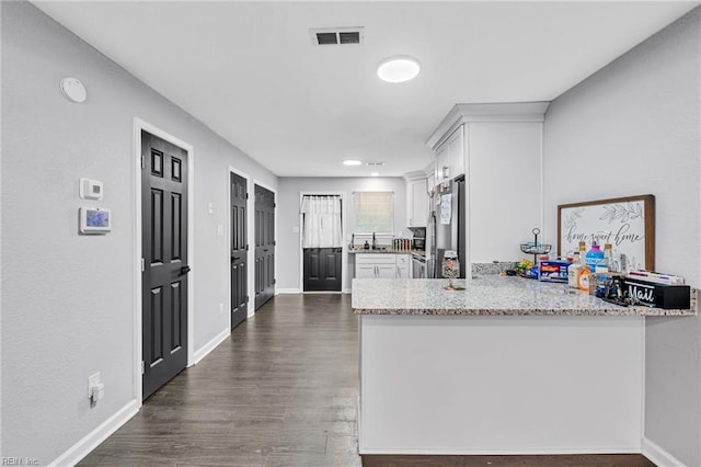 kitchen featuring white cabinetry, light stone counters, stainless steel refrigerator, and dark hardwood / wood-style floors