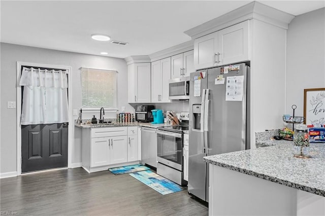 kitchen featuring dark wood-type flooring, light stone counters, sink, white cabinetry, and appliances with stainless steel finishes