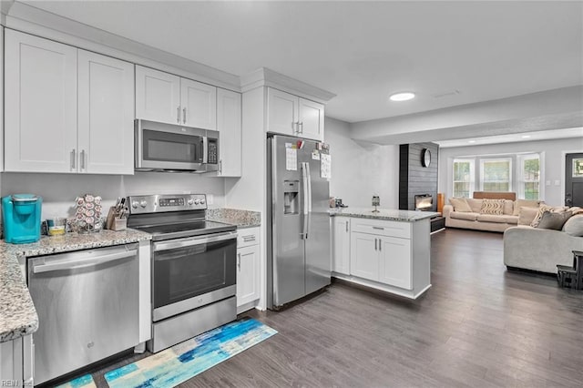 kitchen with white cabinetry, a fireplace, stainless steel appliances, and dark hardwood / wood-style floors