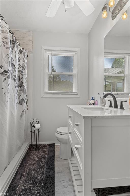 bathroom with toilet, ceiling fan, vanity, and curtained shower