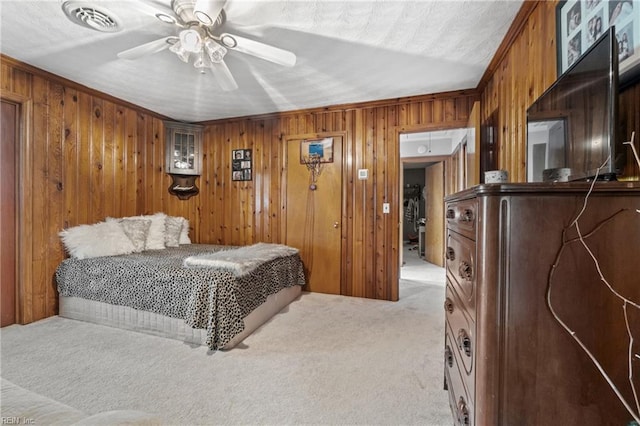 bedroom with ornamental molding, light colored carpet, wood walls, and ceiling fan