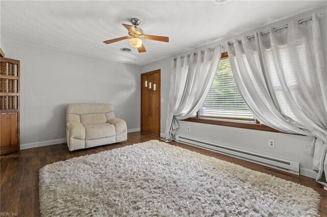 sitting room featuring ceiling fan, baseboard heating, and dark hardwood / wood-style floors