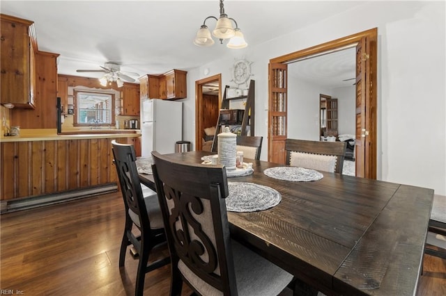 dining space with ceiling fan with notable chandelier and dark wood-type flooring