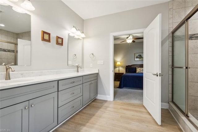 bathroom featuring an enclosed shower, vanity, wood-type flooring, and ceiling fan