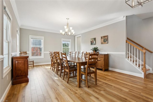 dining space featuring a chandelier, light wood-type flooring, and crown molding