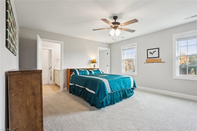 bedroom with light carpet, ceiling fan, and connected bathroom