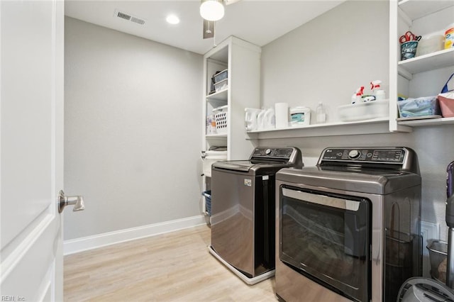 laundry area with washing machine and clothes dryer, ceiling fan, and light hardwood / wood-style flooring