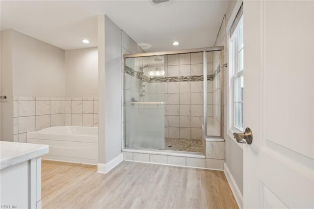 bathroom with hardwood / wood-style flooring, vanity, and shower with separate bathtub