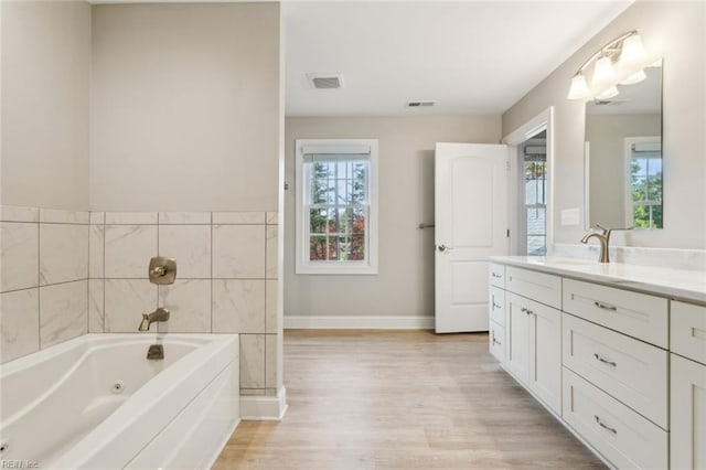 bathroom with wood-type flooring, a healthy amount of sunlight, vanity, and a bath