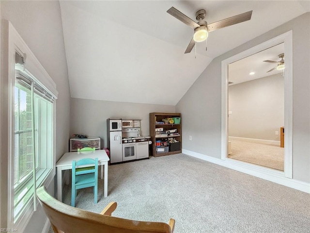 playroom with ceiling fan, vaulted ceiling, carpet flooring, and a healthy amount of sunlight