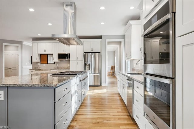 kitchen featuring white cabinets, sink, light wood-type flooring, appliances with stainless steel finishes, and range hood