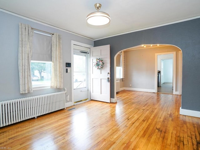 unfurnished room with radiator heating unit, light wood-type flooring, and crown molding