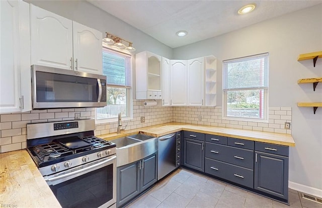 kitchen with white cabinets, stainless steel appliances, a healthy amount of sunlight, and butcher block countertops