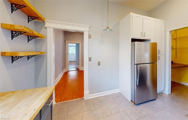 kitchen with wood counters, white cabinetry, light wood-type flooring, decorative light fixtures, and stainless steel fridge