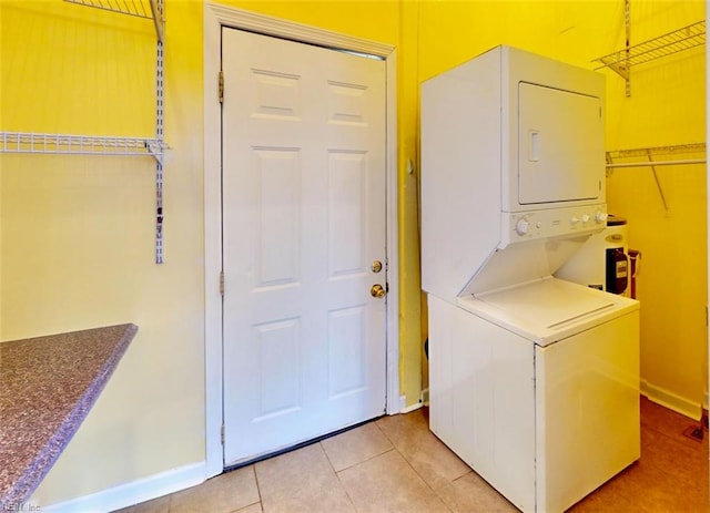 washroom with stacked washing maching and dryer and light tile patterned floors