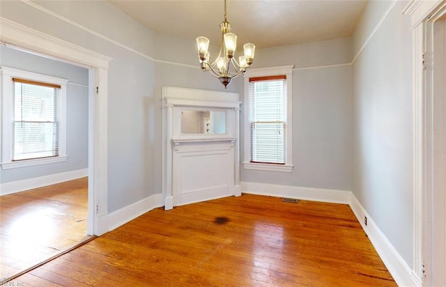 unfurnished dining area with a healthy amount of sunlight, hardwood / wood-style flooring, and a chandelier